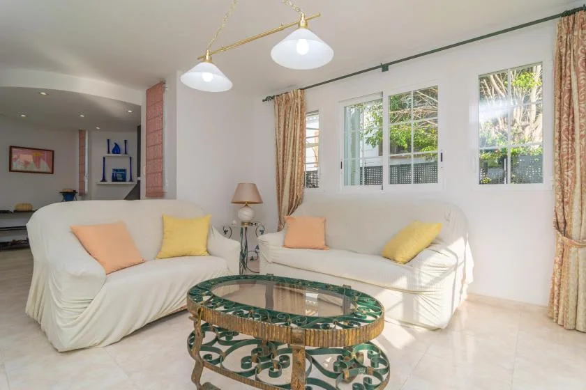 Una sala luminosa con asientos blancos y una mesa de centro de vidrio.