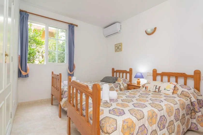 Un dormitorio luminoso con camas de madera y una ventana enmarcada por cortinas azules.
