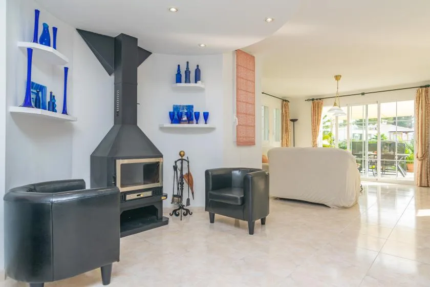 Una sala luminosa con chimenea, asientos y puertas de vidrio que dan a un patio.