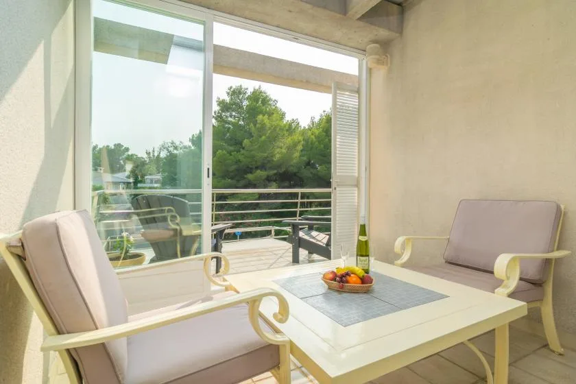 Una luminosa zona de estar en el patio, con una mesa junto a grandes puertas de vidrio.