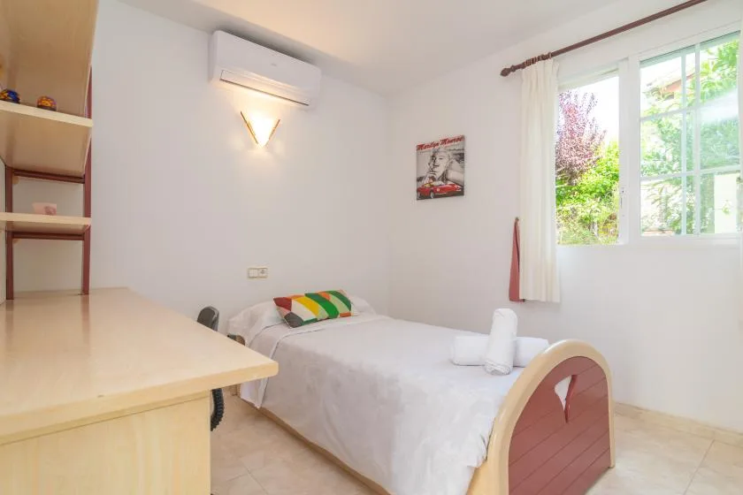 Un dormitorio luminoso con una cama individual junto a una ventana grande.