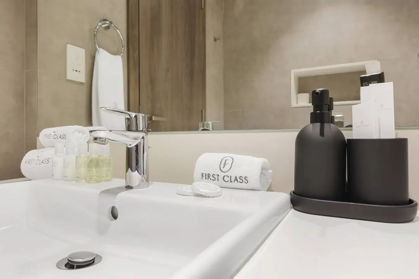 Un lavabo de baño con lavabo blanco, grifo cromado y artículos de aseo.