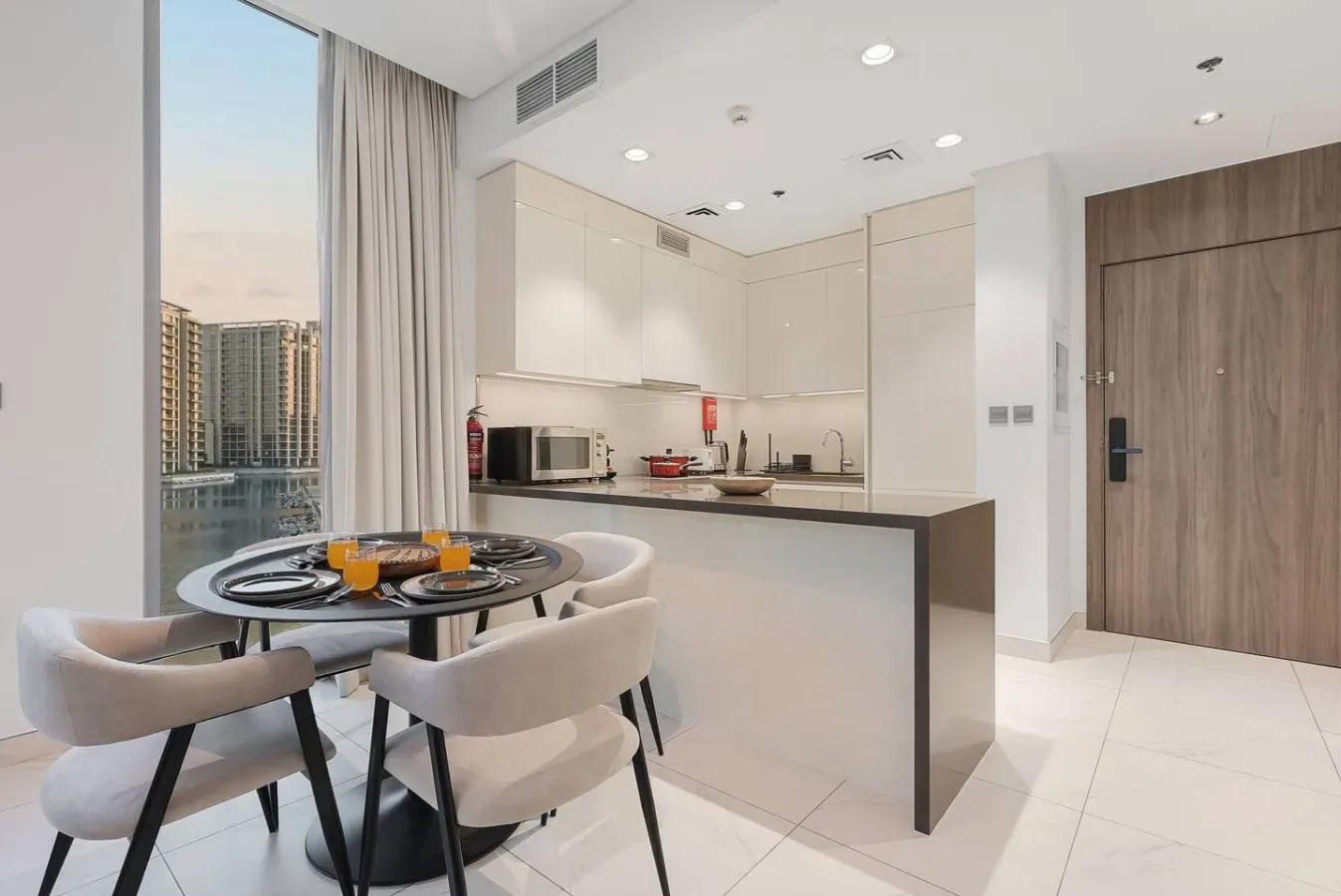 Una cocina luminosa con zona de comedor y una mesa redonda junto a una gran ventana.