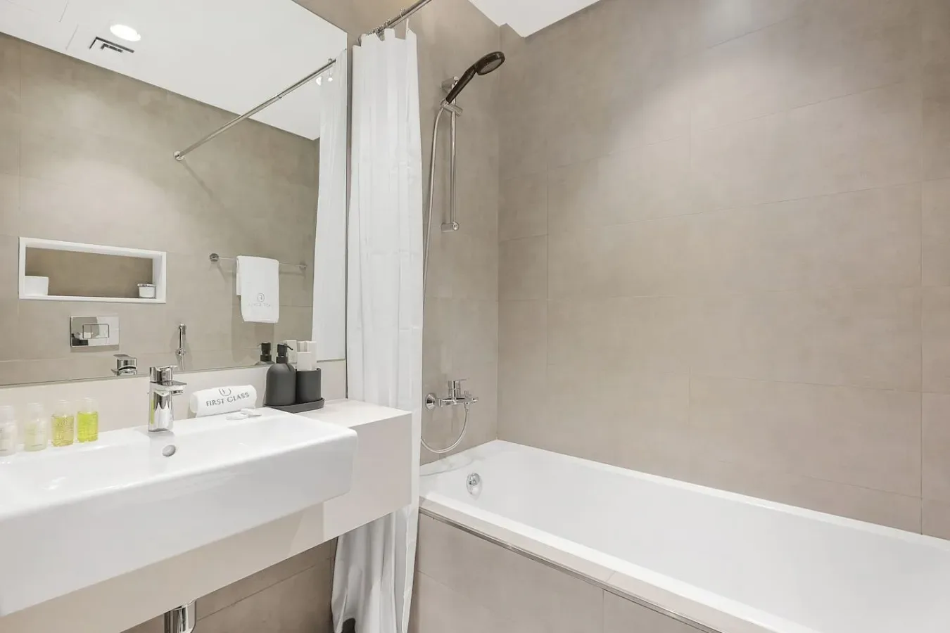 Un baño con lavabo, espejo y bañera detrás de una cortina de ducha.