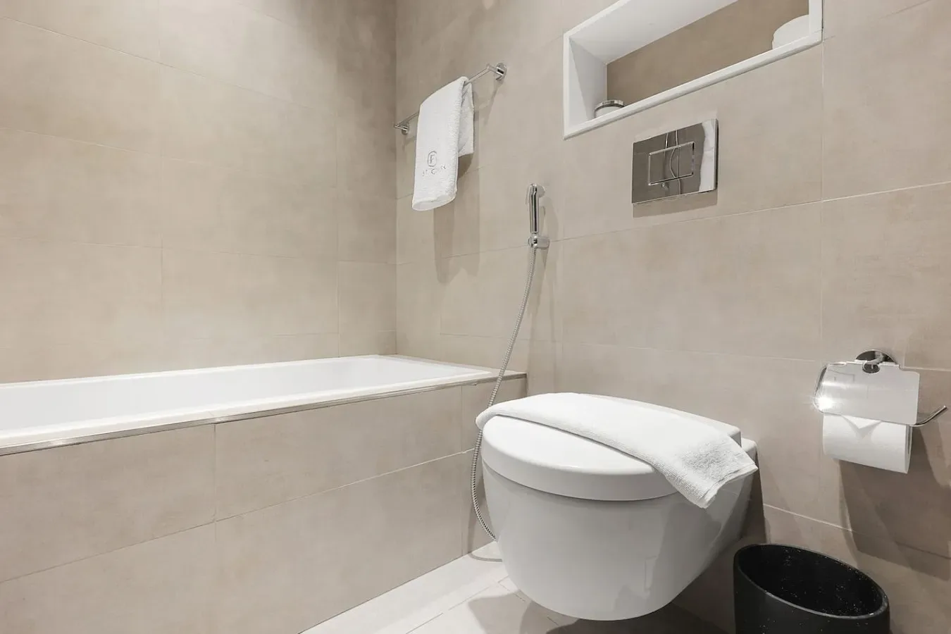 Un baño con paredes de azulejos, bañera e inodoro.