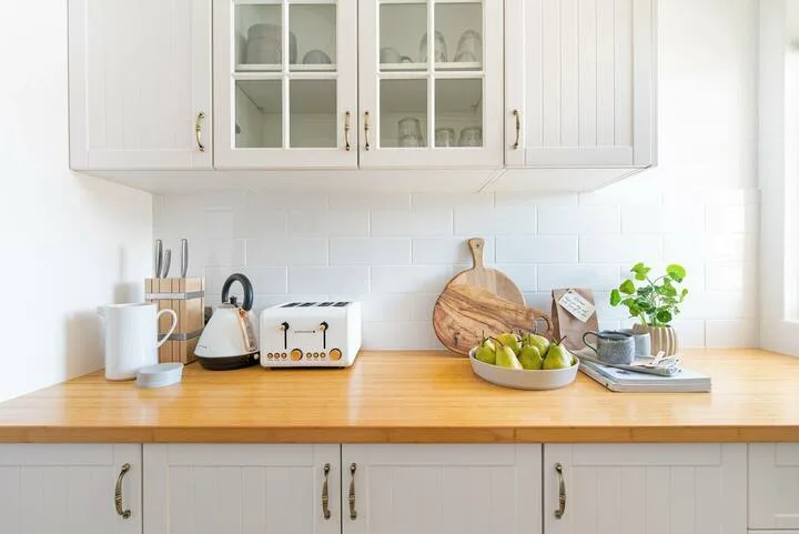 Una luminosa encimera de cocina tiene una tostadora, un frutero y una pequeña planta en maceta.