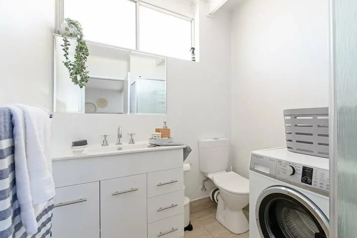 Un baño luminoso con lavabo, inodoro y lavadora.