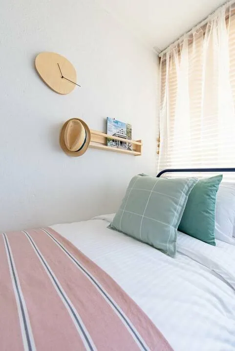 Un dormitorio con ropa de cama a rayas, almohadas y una ventana con cortinas claras.