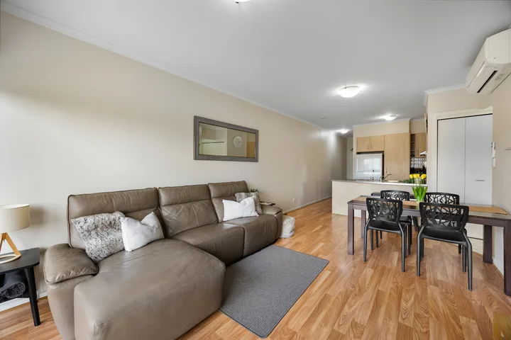 Una sala y comedor con sofá seccional y una mesa junto a la cocina.