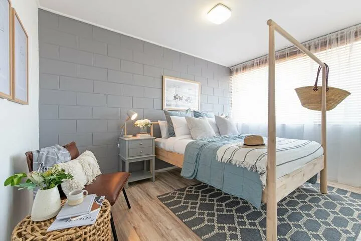 Dormitorio con una cama, una mesita de noche y una alfombra estampada.