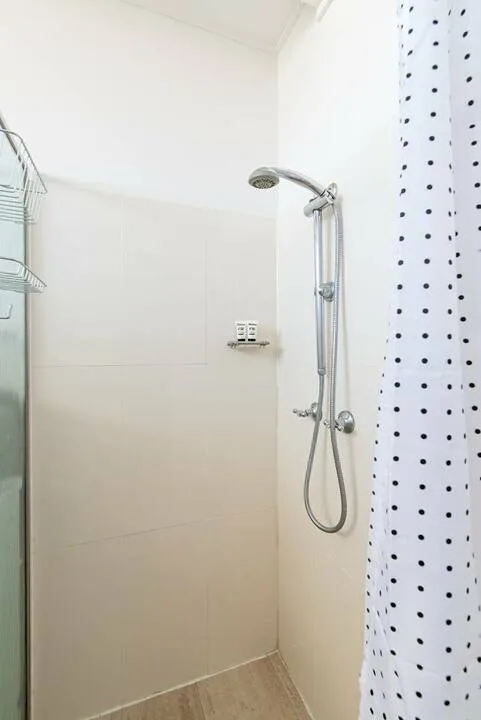 Una zona de ducha con ducha de mano y una cortina de puntos.