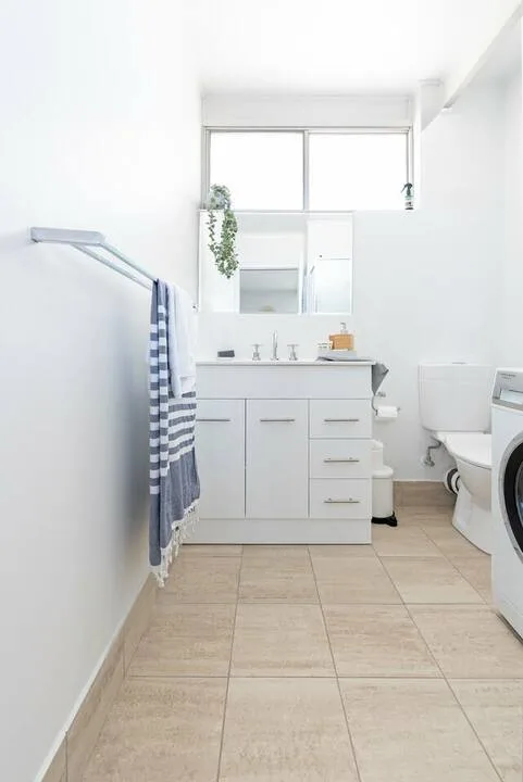 Un baño luminoso con lavabo, inodoro y suelo de baldosas.
