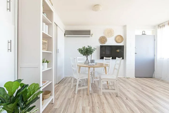 Un comedor luminoso con una mesa, asientos y un televisor.