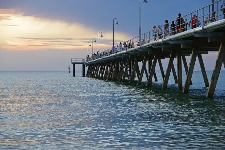 Un largo muelle se extiende sobre el agua bajo un cielo nublado al atardecer.