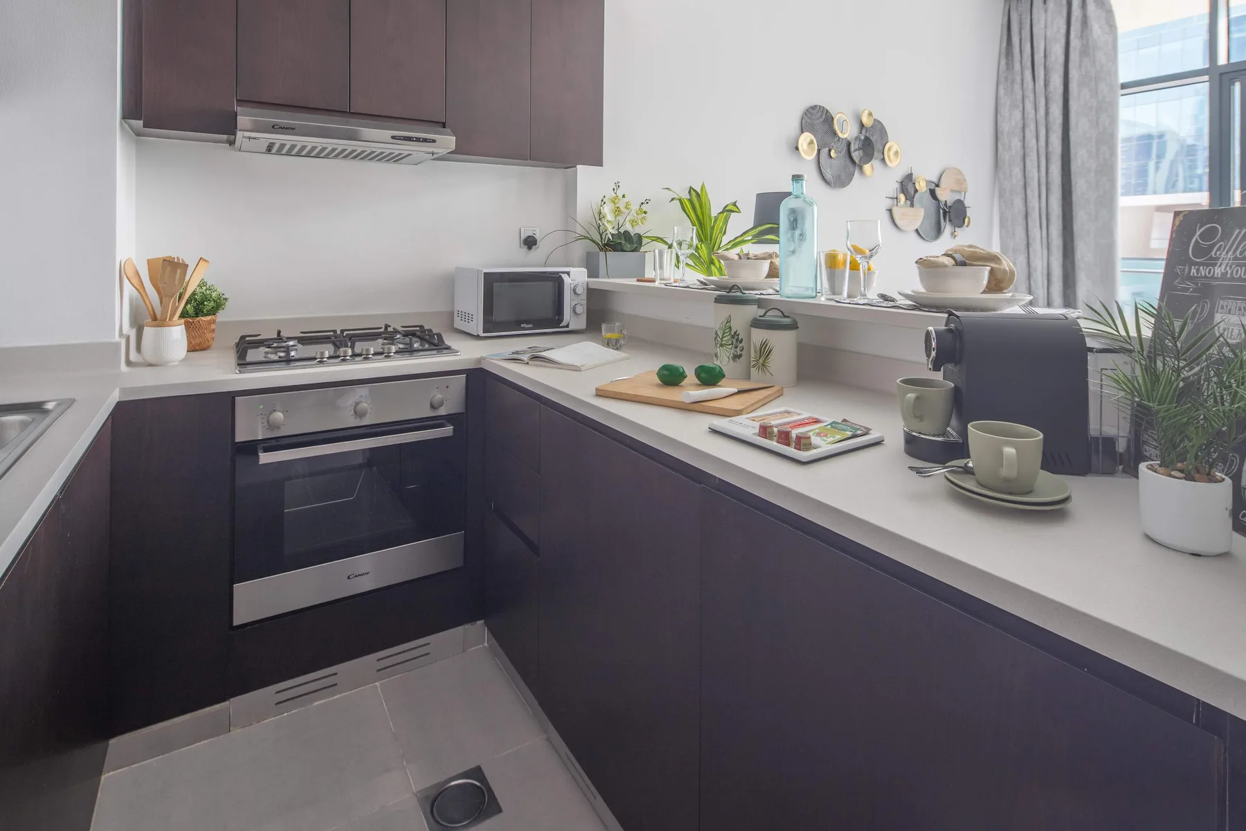 Una cocina moderna con gabinetes oscuros, una estufa y plantas sobre la encimera.