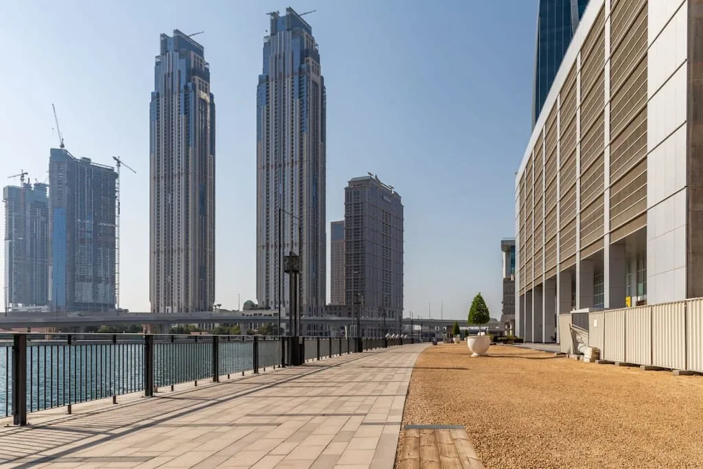 Una terraza exterior da a un horizonte urbano junto al agua, con un camino pavimentado junto al edificio.