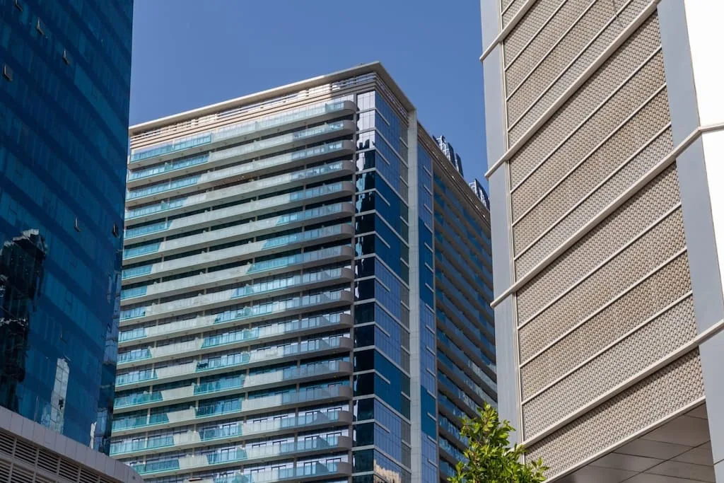 Escena urbana con edificios de oficinas modernos bajo un cielo azul despejado.