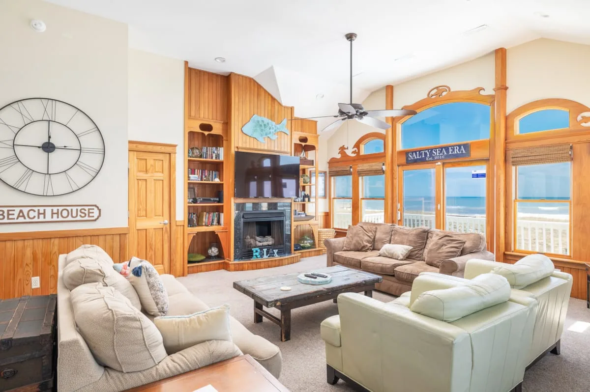 A bright living room with seating arranged around a coffee table and large windows.