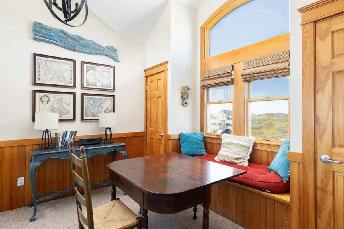 Un luminoso rincón de comedor con una mesa de madera y un asiento junto a la ventana.