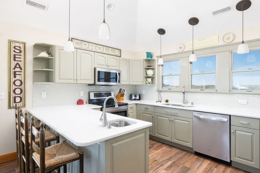 Una cocina luminosa tiene una isla central y ventanas sobre las encimeras.