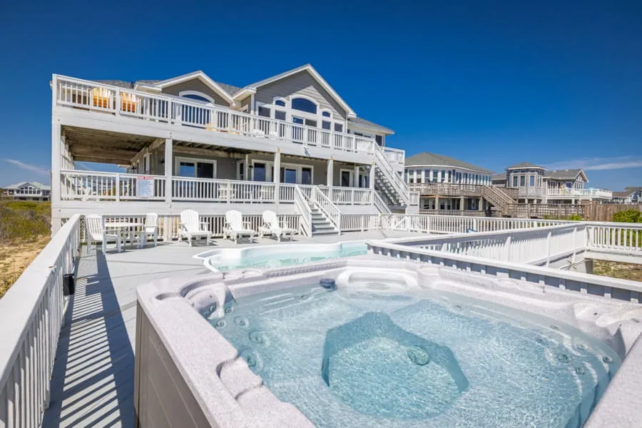 Una casa costera con una amplia terraza y un jacuzzi exterior con burbujas.