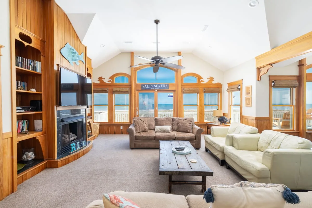 A bright living room with seating, a coffee table, and large windows.