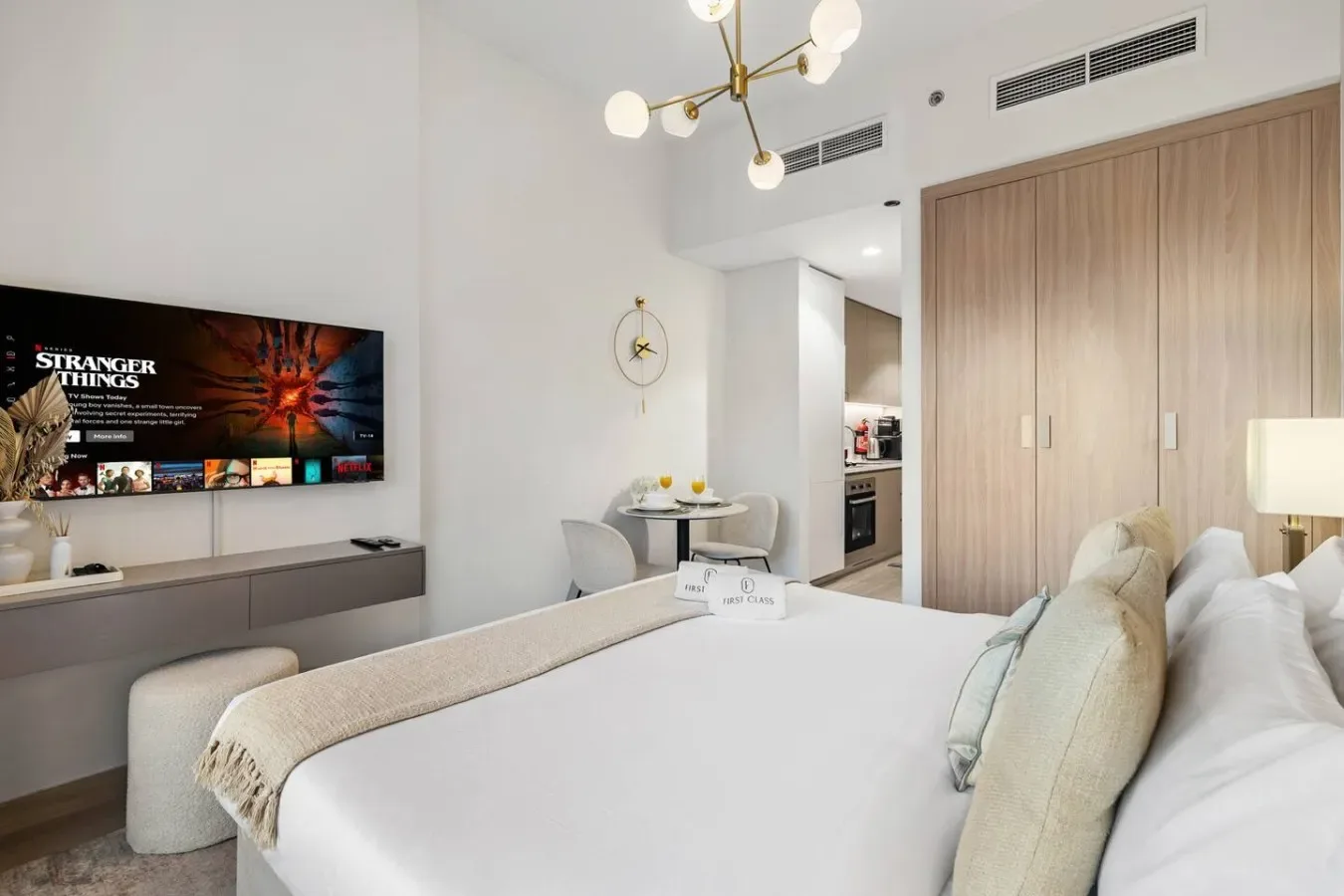 A bright bedroom with a bed, a wall-mounted television, and built-in cabinets.