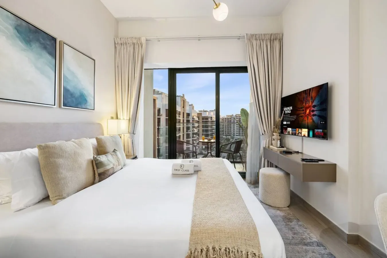A bedroom with a large bed, framed artwork, and sliding glass doors opening onto a balcony.