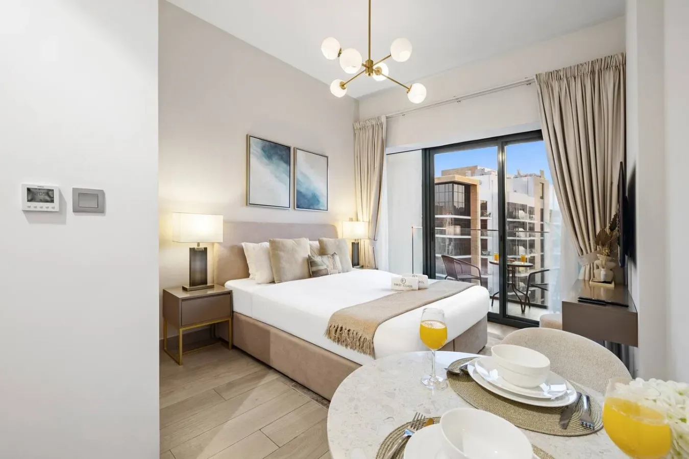 A bright bedroom with a large bed and sliding glass doors opening onto a balcony.