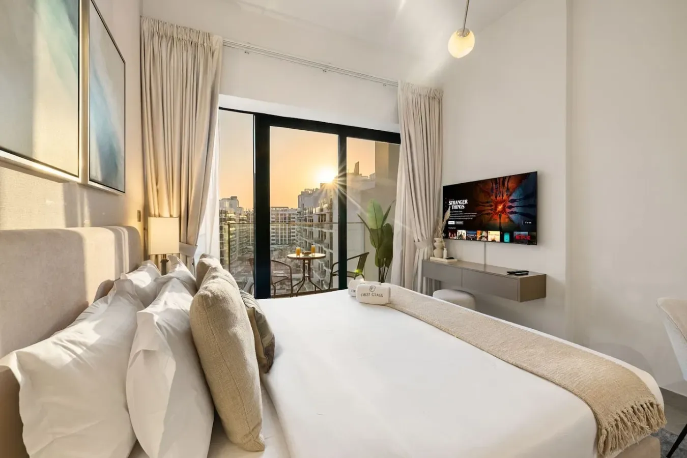 A bedroom with a bed facing a television beside large glass doors.