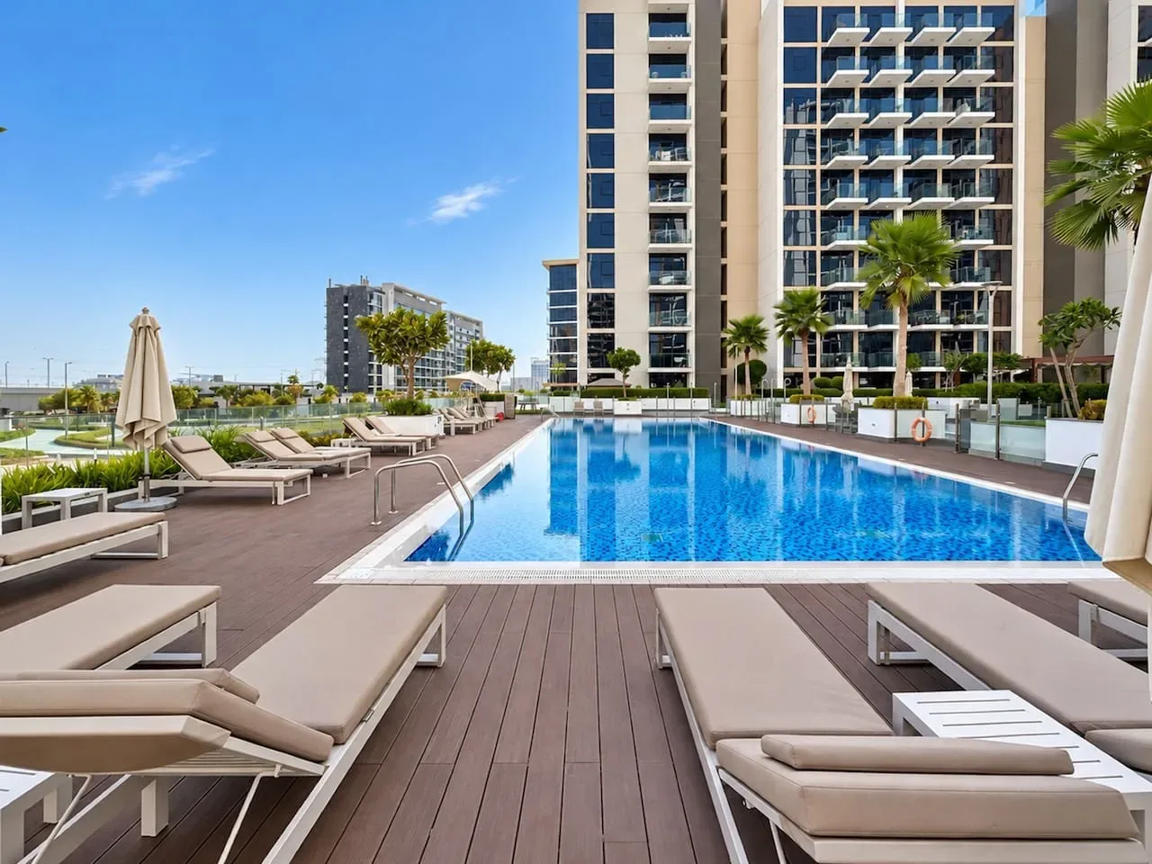 A rooftop pool is surrounded by lounge seating and modern apartment buildings.