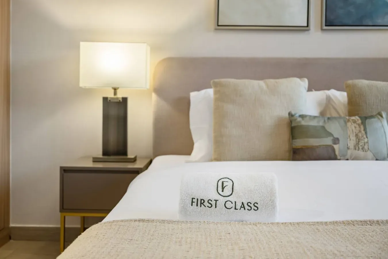 A neatly made bed with layered pillows and a bedside lamp.