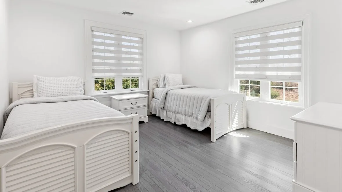 Un dormitorio luminoso con dos camas y ventanas amplias.