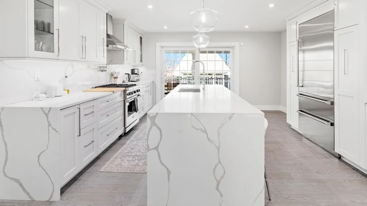 Una cocina luminosa con gabinetes blancos y una gran isla central.