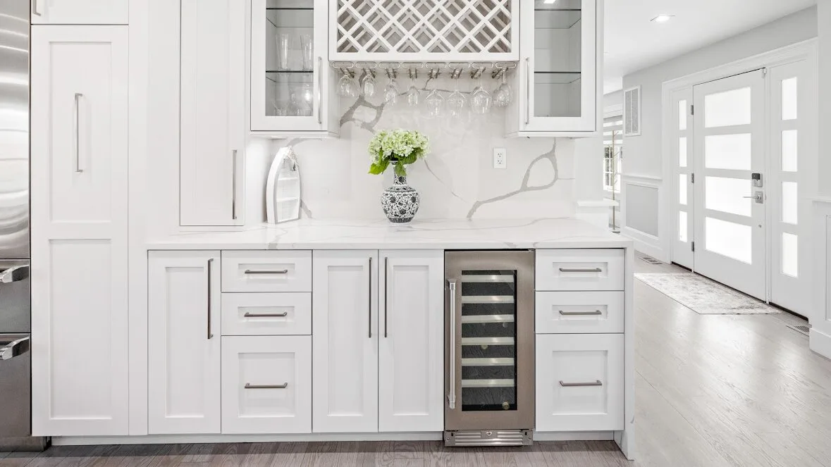Una cocina blanca y luminosa con gabinetes, una encimera y un enfriador de vino integrado.