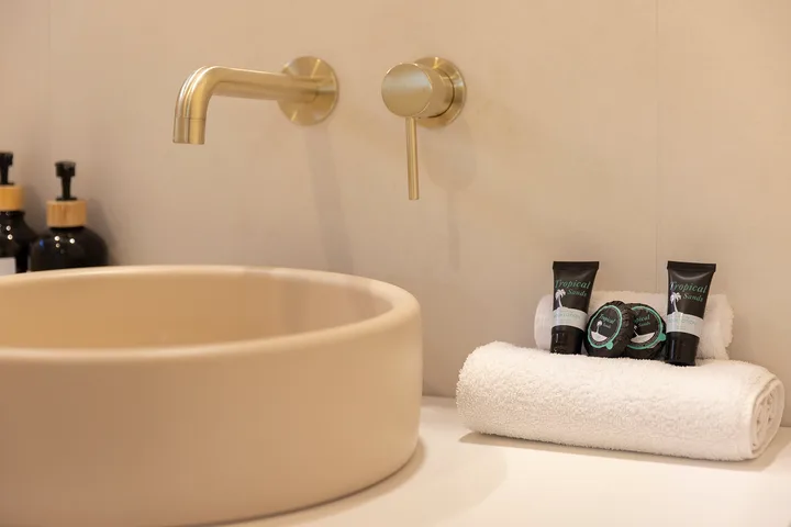 Un lavabo de baño con una pila redonda, grifo de pared y toalla doblada.