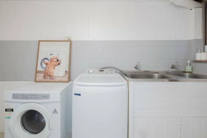 Un cuarto de lavandería con lavadoras junto a un fregadero de servicio.