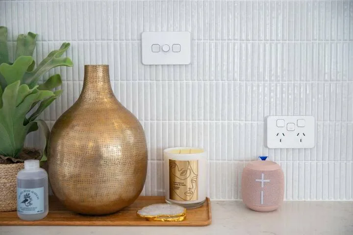 Una encimera de baño con recipientes decorativos frente a una pared de azulejos.
