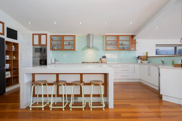 Una cocina moderna y luminosa con una isla central y suelo de madera.
