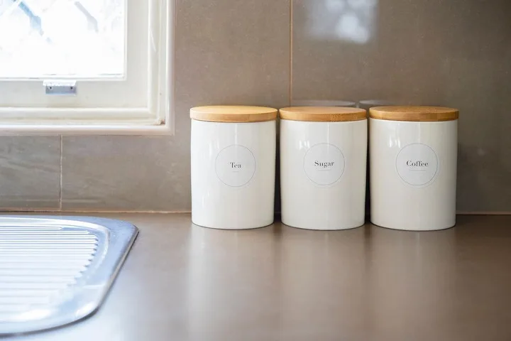 Encimera de cocina con tres recipientes blancos junto a una ventana.