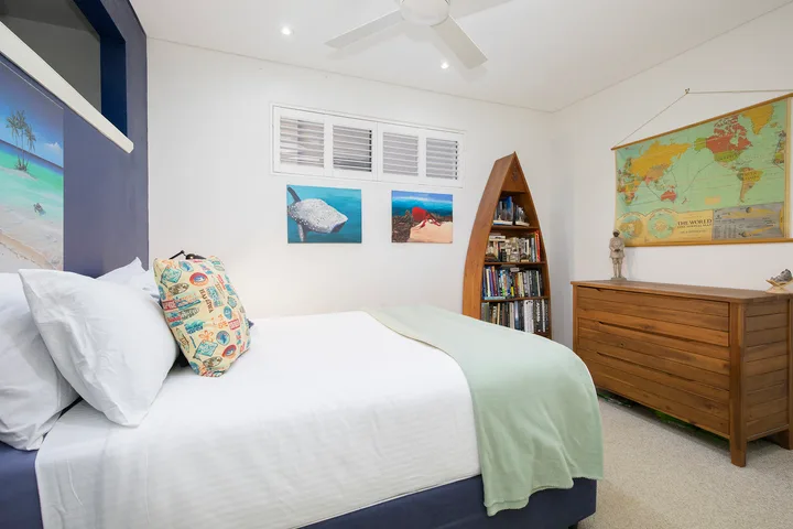 Un dormitorio con una cama, una cómoda de madera y un mapa en la pared.