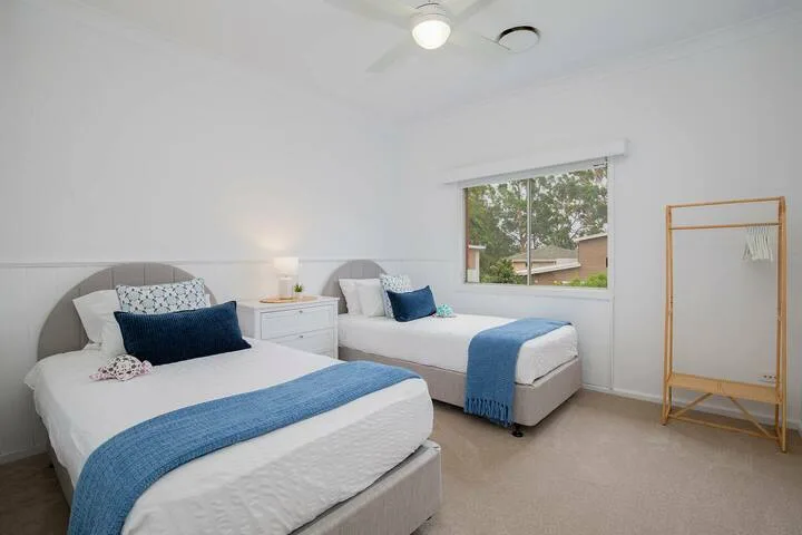 Un dormitorio luminoso con dos camas vestidas con ropa de cama blanca y azul.