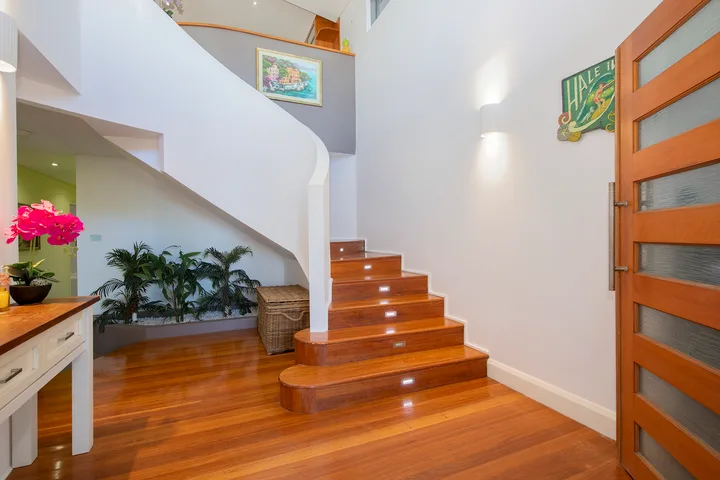 Un recibidor interior con una escalera curva y pisos de madera pulida.