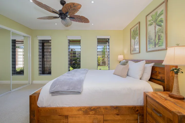 Un dormitorio con una cama de madera, ropa de cama blanca y ventanas en la pared.