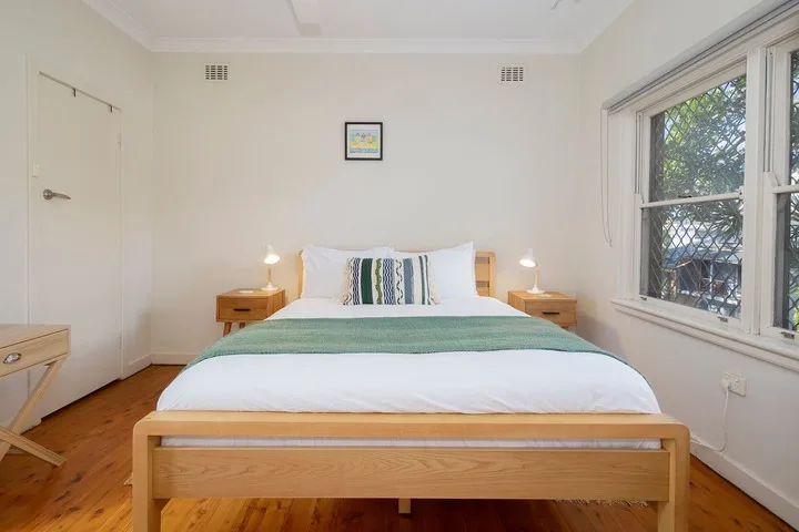 Un dormitorio con una cama bien tendida y una ventana grande.