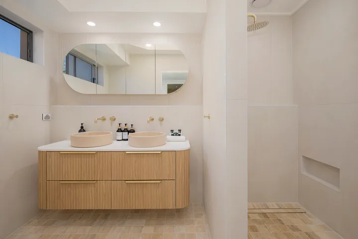 Un baño luminoso con un tocador de dos lavabos y una zona de ducha.