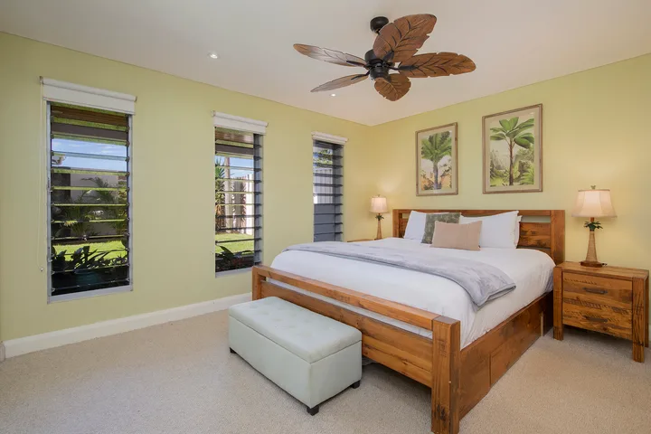 Dormitorio con cama de madera, ropa de cama clara y un banco a los pies.