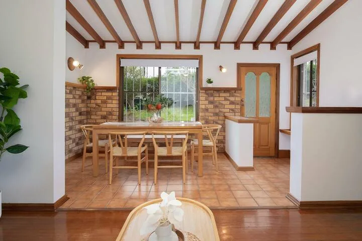Comedor con una mesa de madera bajo vigas expuestas en el techo.