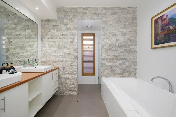 Un baño luminoso con un tocador largo y una bañera.