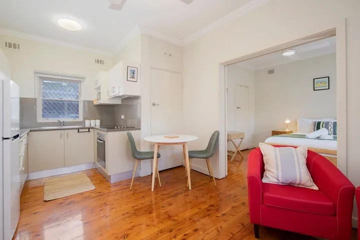 Una cocina abierta y zona de estar con un sillón rojo junto a la mesa.